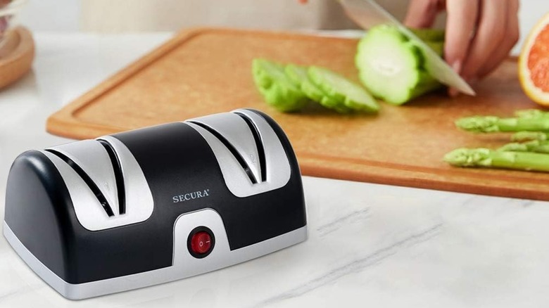 A person slicing a cucumber by a Secura Electric Knife Sharpener