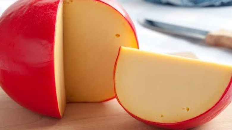 Yellow cheese with a red peel on cutting board