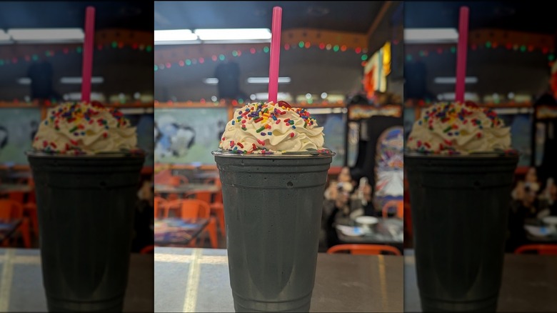 Large black Licorice milkshake garnished with whipped cream, rainbow sprinkles and a cherry