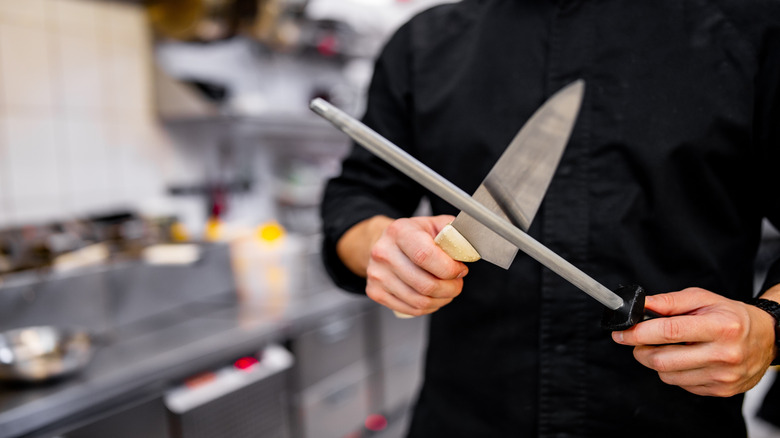Chef in black sharpening a knife