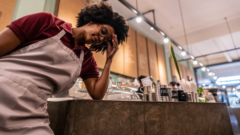 Server leans against a counter at the restaurant with head in hand