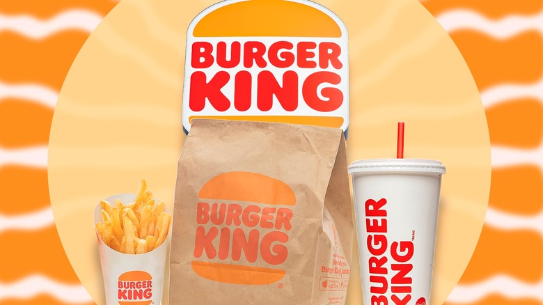 Burger King to-go bag, fries, and a drink underneath the chain's logo, against an orange background