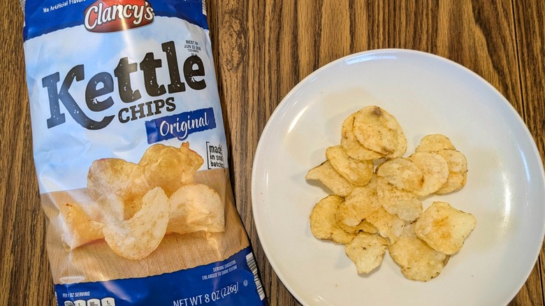 Blue bag of Clancy's kettle chips next to chips on white plate