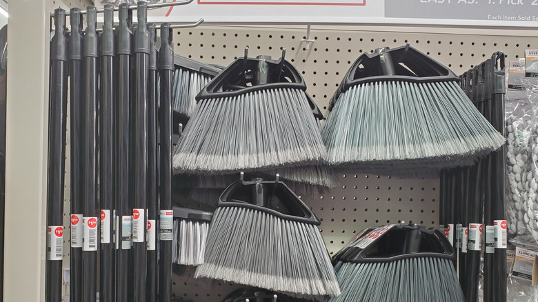 Broom heads and handles hanging on a rack at Dollar Tree