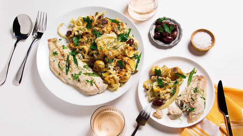 Sheet Pan Snapper with Potatoes and Fennel on white plates with cutlery and glasses