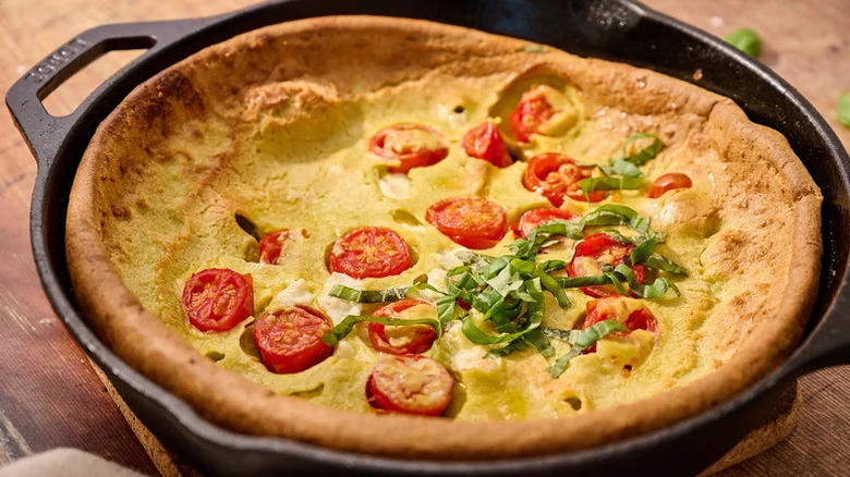 Savory Dutch baby with tomatoes in cast iron pan