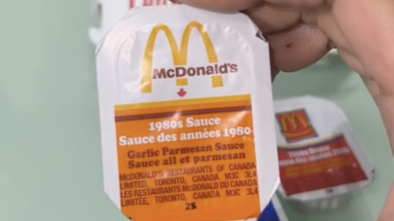 Hand holding up a container of McDonald's Garlic Parmesan 1980s Sauce