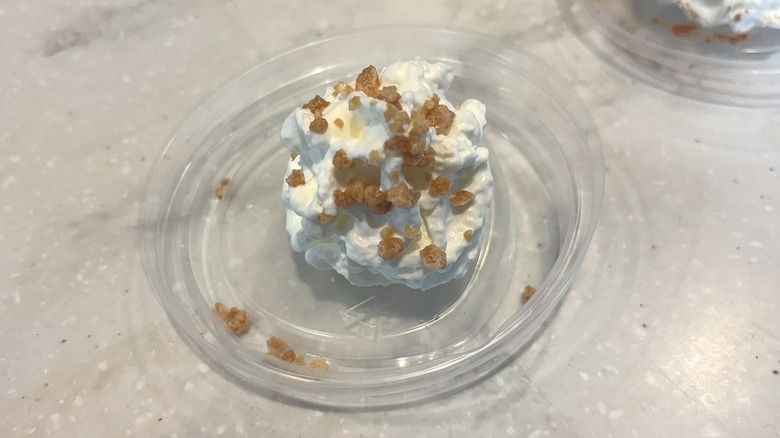 Whipped cream topped with caramel crunch on marble counter