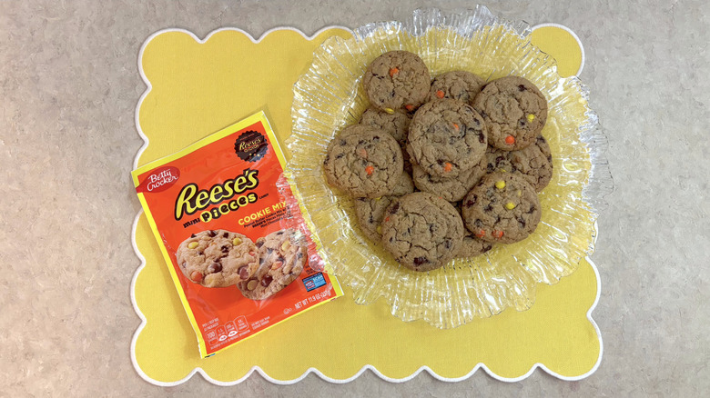 Betty Crocker Reese's Pieces cookies on clear platter on yellow placemat