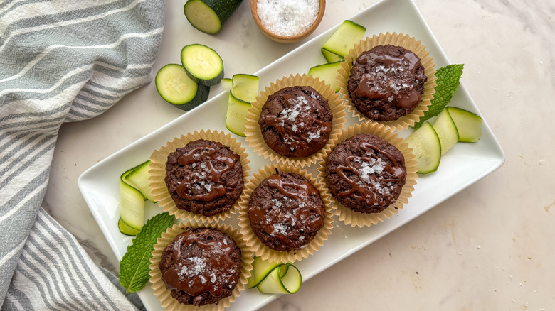 White tray with chocolate muffins, zucchini strands, and mint leaves
