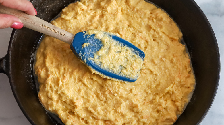 spreading cornbread batter in cast iron skillet