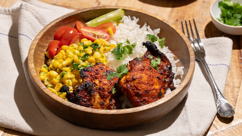 Pollo asado served with corn, tomatoes, white rice, and garnished with cilantro