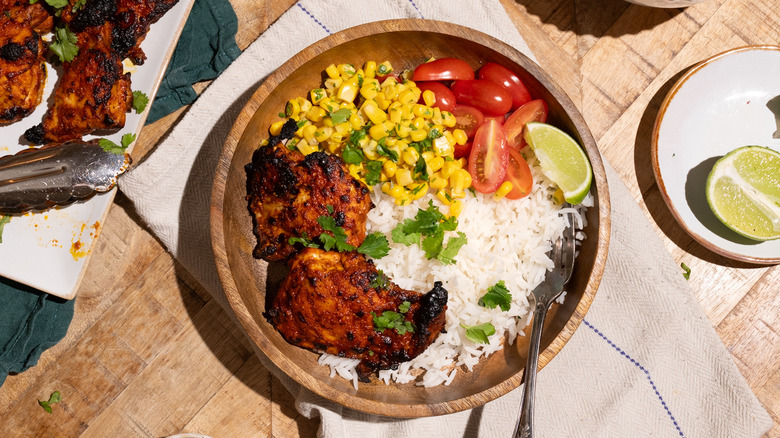 Plate of pollo asado, corn, tomatoes, lime wedge, white rice, and cilantro