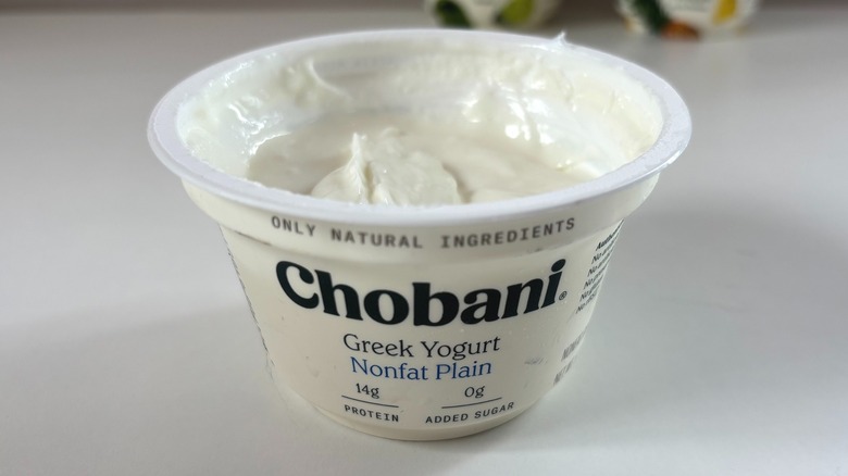 Open Chobani nonfat plain greek yogurt cup on white table