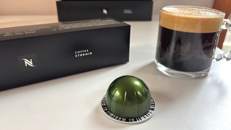 Nespresso Stormio pod, box, and mug of coffee on white table