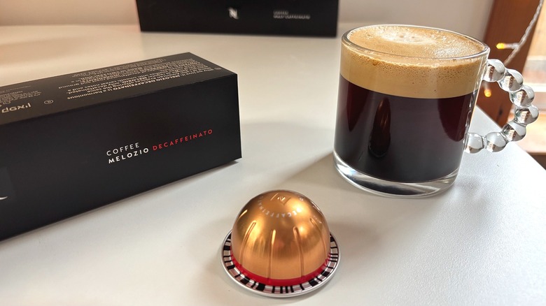 Nespresso Melozio Decaffeinato pod, box, and mug of coffee on white table