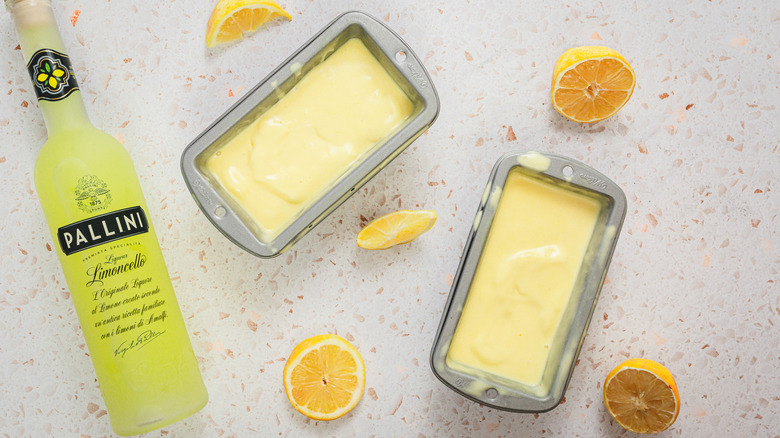 Two small trays of gelato alongside limoncello bottle and lemons
