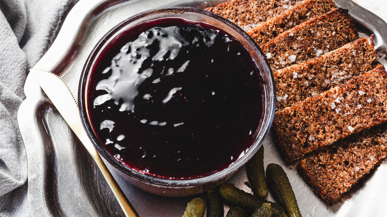 Chicken liver mousse with black currant topping alongside dark rye toast and cornichons