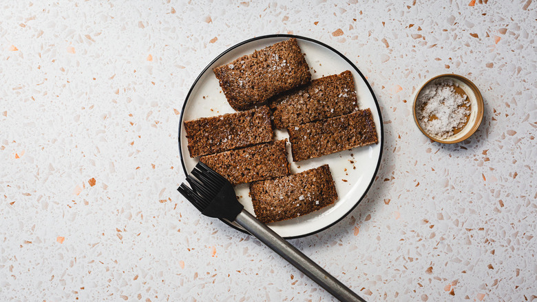 Dark rye slices on plate with brush and salt