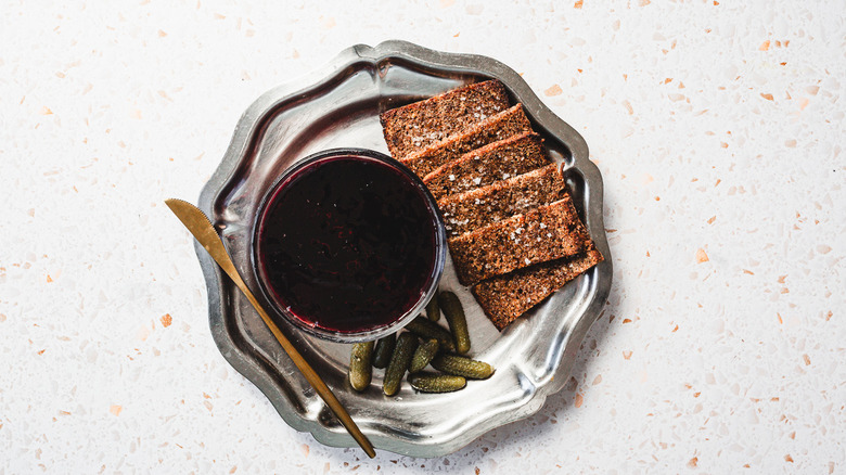 Chicken liver mousse with black currant topping alongside dark rye toast and cornichons on tray