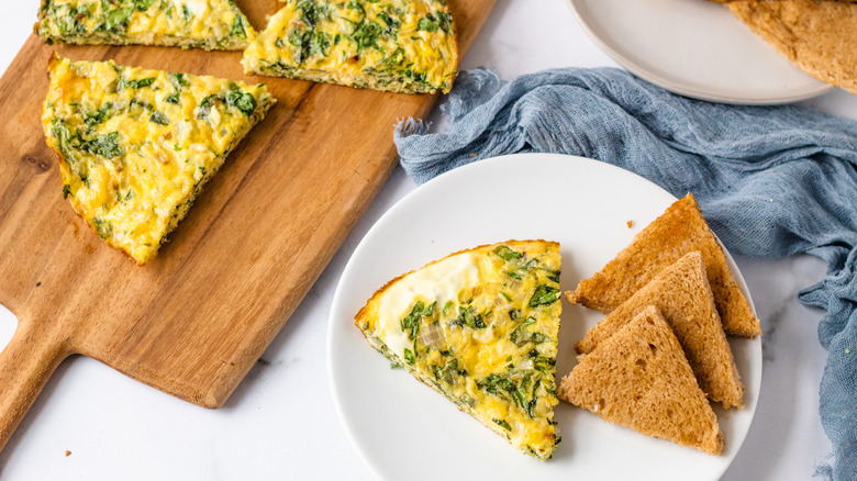 slice of quiche on plate and other slices on wooden tray