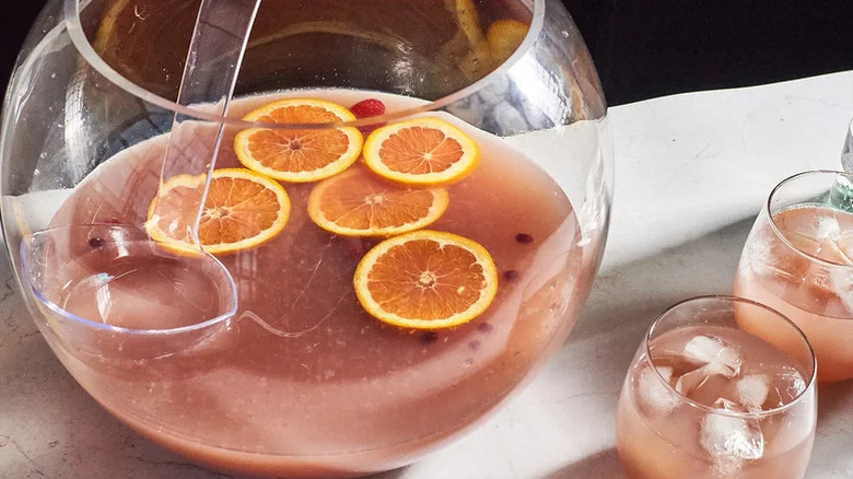 a punch bowl filled with a pink punch and slices of oranges