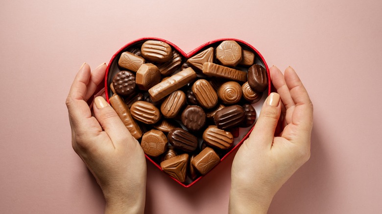 Hands cupping a heart-shaped Valentine's Day chocolate box