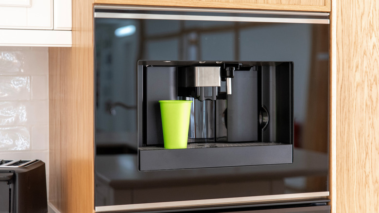 Built-in black coffee machine with a green cup
