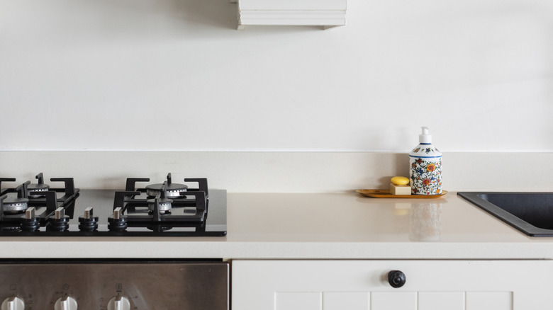 Empty beige stone kitchen countertop with a stove and a soap dispenser