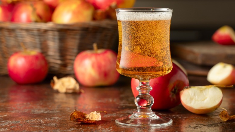A glass of apple cider with fresh red apples