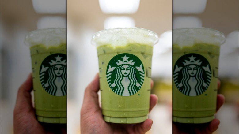 mans hand holding iced matcha latte from Starbucks