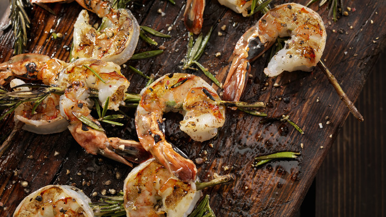 Grilled shrimp skewers seasoned on a wooden board