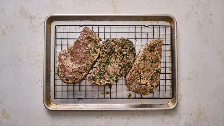 steaks with marinade on wire rack