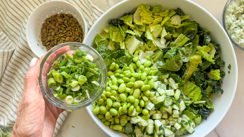 hand adding onions to salad