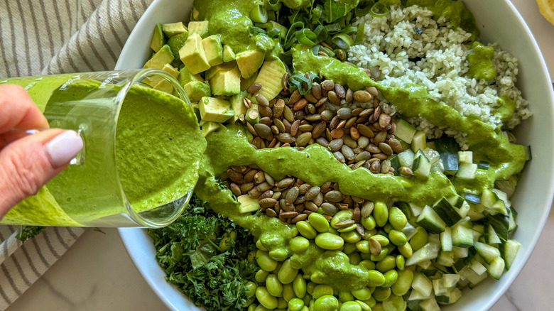 hand adding dressing to salad