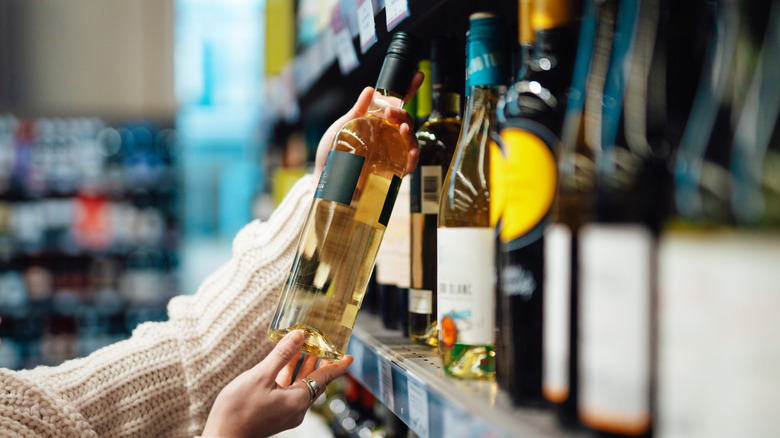 shopper examining bottles of white wine