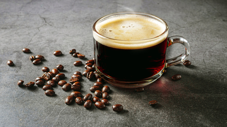 A cup of espresso surrounded by beans