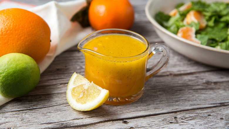 Citrus vinaigrette in serving cup next to citrus fruits