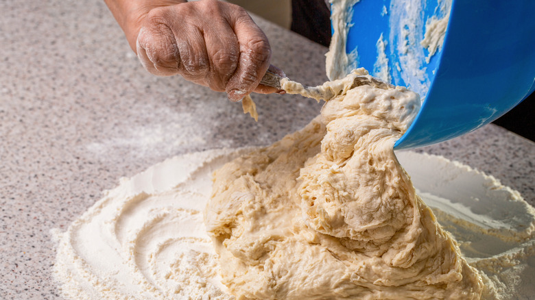 Pouring sourdough discard from a bowl directly on the table