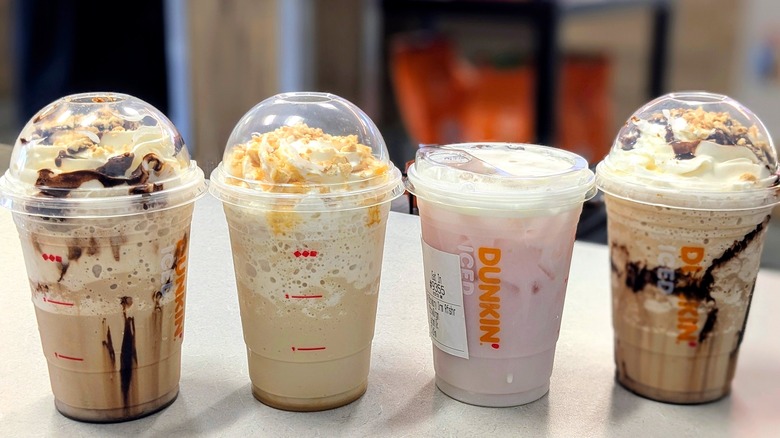 Four Dunkin' drinks lined up on a grey table inside the coffeeshop