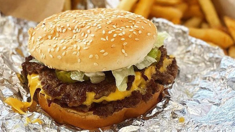Fives Guys burger with fries in the background