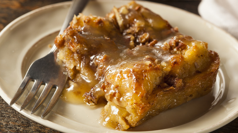 Bread pudding with bourbon sauce next to fork on plate