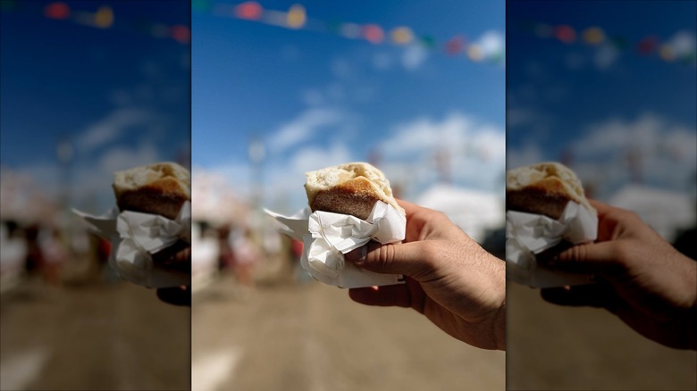 Hand holding buttermilk biscuit in front of sky at Mississippi State Fair