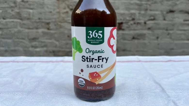 A bottle of 365 Organic Stir-Fry Sauce on a white surface
