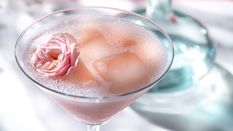 Close-up of a rose cocktail, with a flower floating in pink liquid in a martini glass