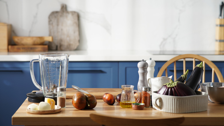Interior of a kitchen with food items and appliances spread on the dining table