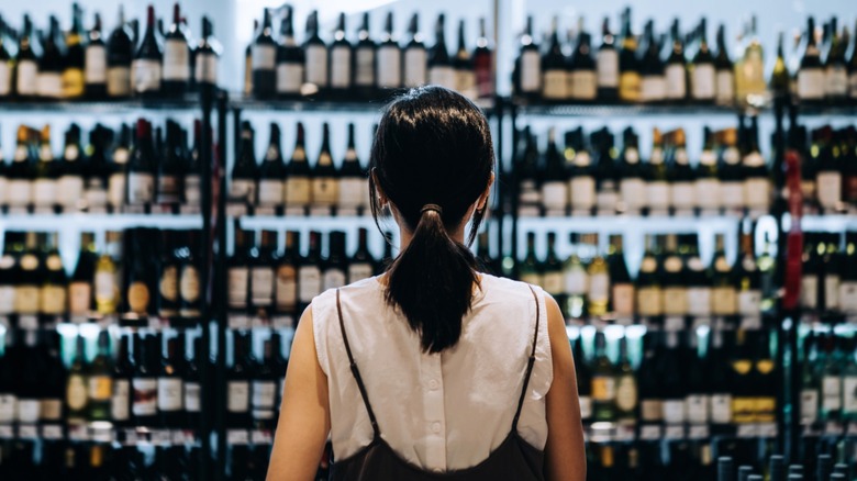 Back view of a shopper browsing bottles at a liquor store