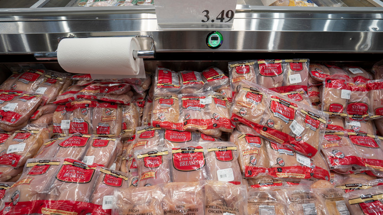 An open cooler section with dozens of Costco chicken breasts in red packaging