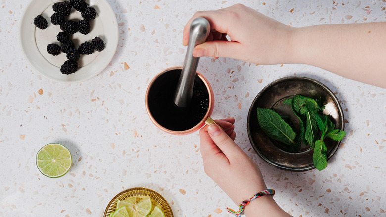 Muddling blackberries in a copper mule glass