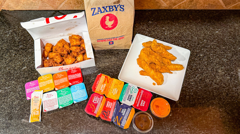 Selection of Zaxby's and Chick-fil-A sauces and chicken on a black countertop